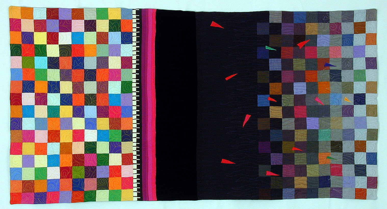 Photo of a quilt, rectangular and landscape format. At left many bright squares create a colorful random gridwork. At the right edge of this area, toward the center of the quilt, several narrow vertical lines separate the colored squares from a very black area which covers about the middle third. In that area, mostly to the right side are some long skinny triangles randomly placed. At the right side, colored squares appear again, but dark and of muted colors, they seem to emerge from the middle darkness.